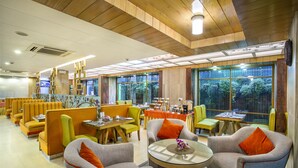 Un restaurante con cabinas y mesas, techo de madera y ventanas amplias.