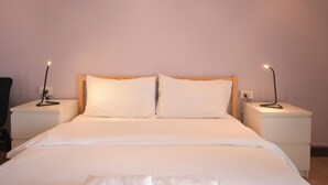 A neatly made bed with white linens, two bedside tables with lamps, and a chair to the left. - ROOM at VIPA (Bangkok)