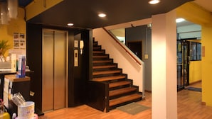 A hotel lobby with a wooden staircase, a reception desk, and a glass door leading to another area. - ROOM at VIPA (Bangkok)