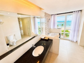 A modern bathroom with a large mirror, a black countertop, a white sink, and a bathtub. - Royal Heritage Pavillion (Pattaya)