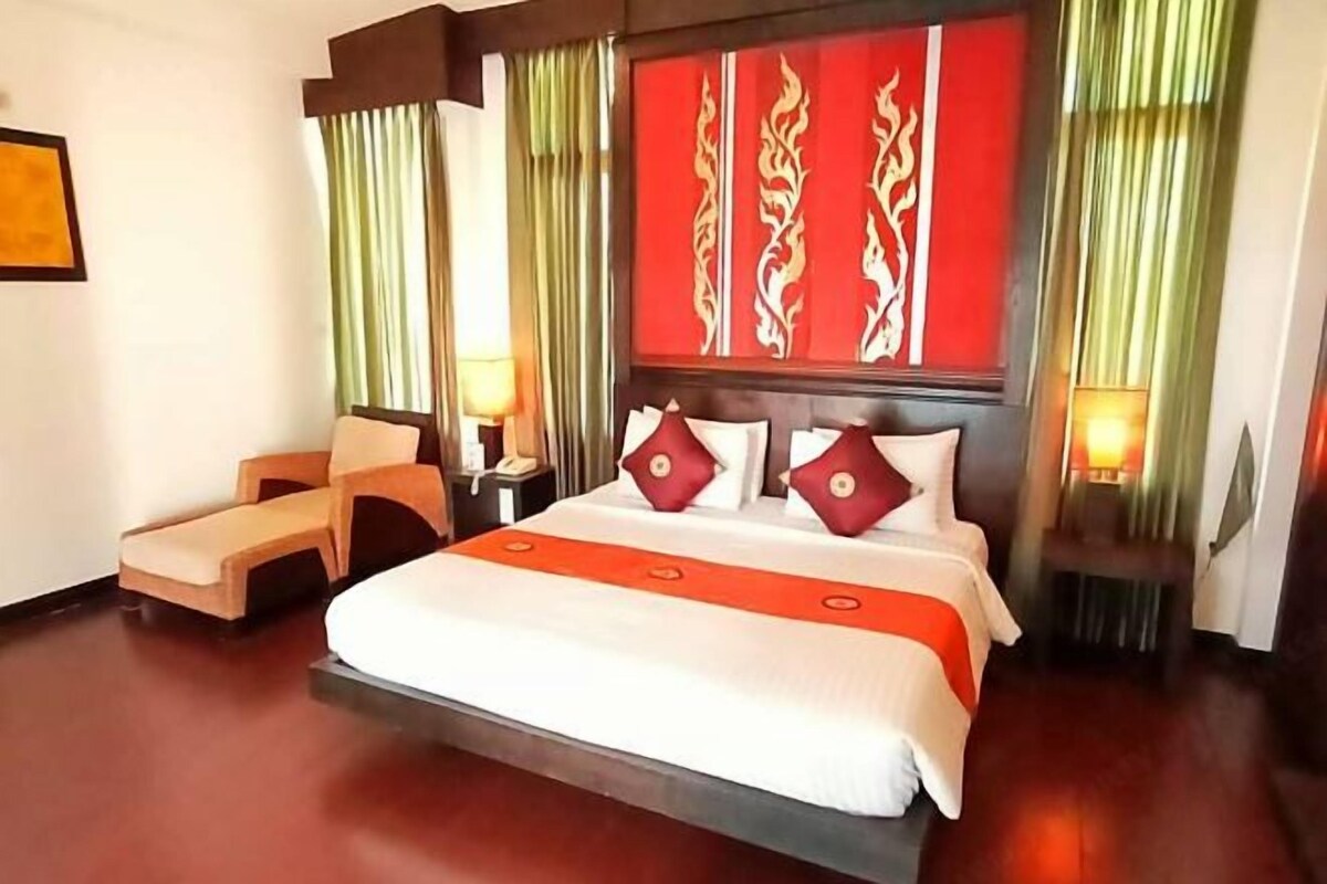 A hotel room with a large bed, two bedside tables, a chair, and curtains.