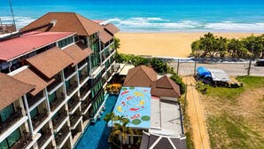A hotel with a swimming pool, a beach view, and a colorful mural.