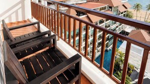 A balcony with a view of a swimming pool and ocean.