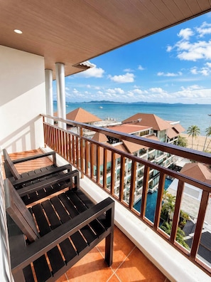 Ein Balkon mit Blick auf ein Schwimmbecken und den Ozean.