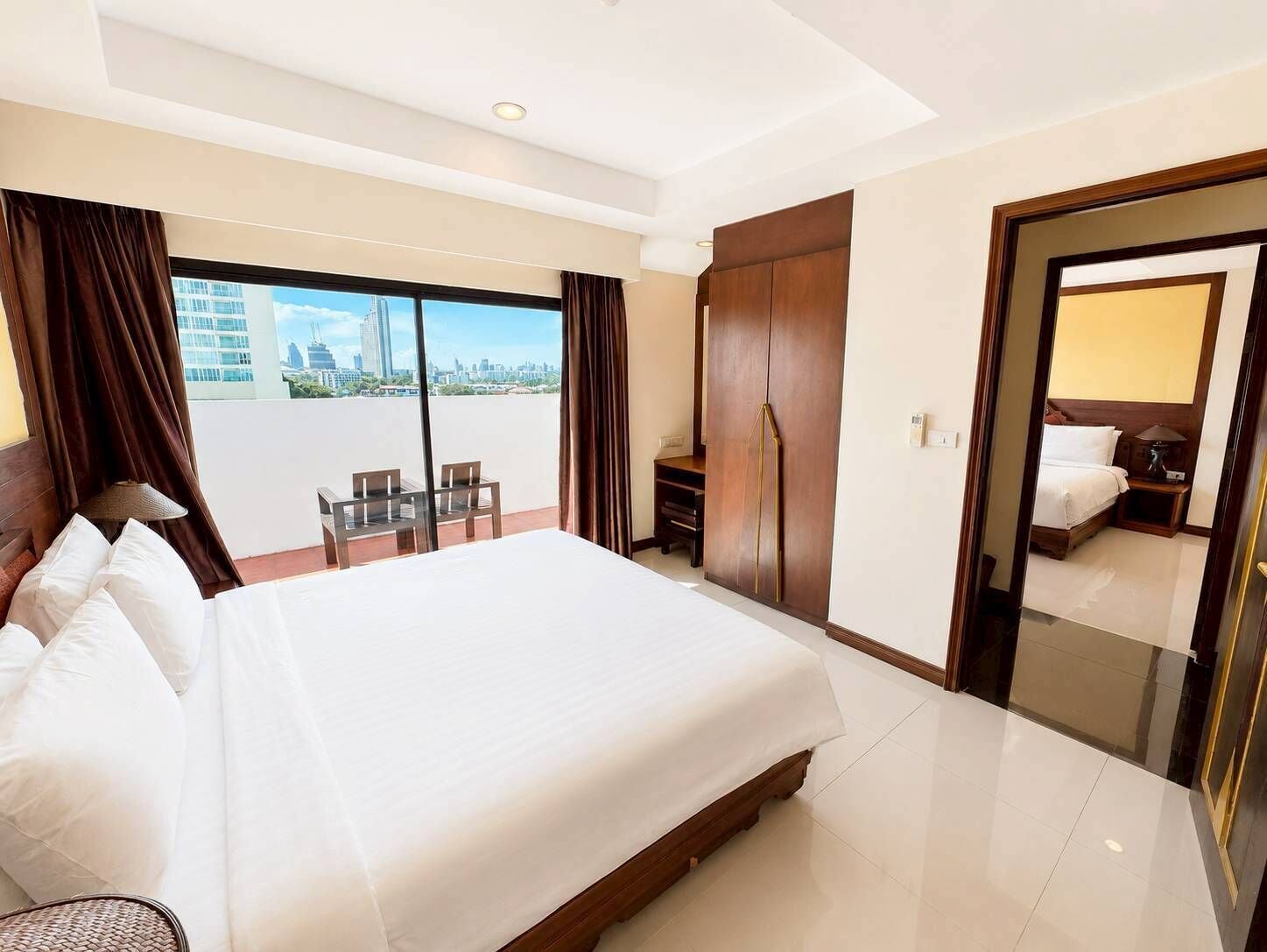 Ein Hotelzimmer mit einem großen Bett, einem Schreibtisch, einem Stuhl, einem Kleiderschrank und Blick auf die Stadt.