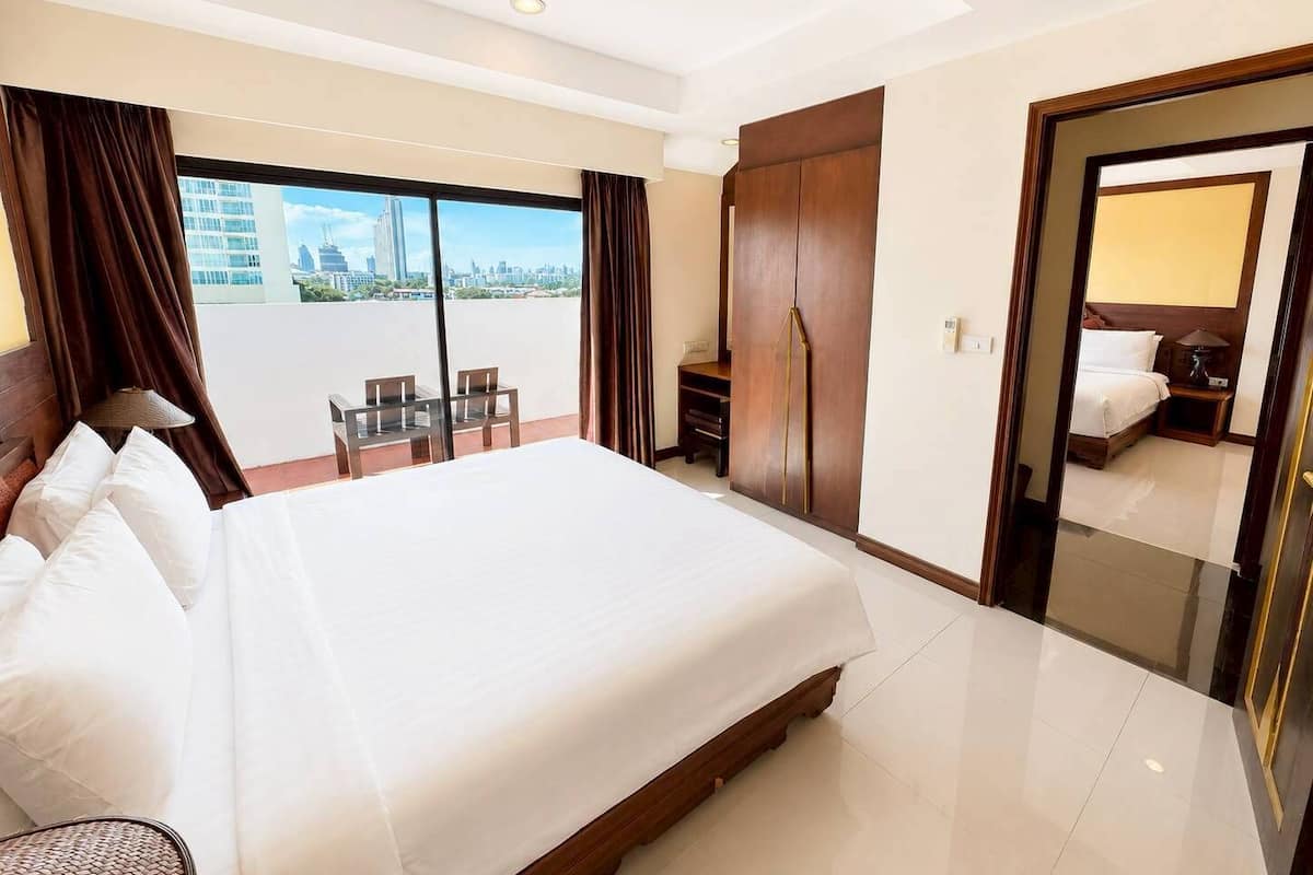 Ein Hotelzimmer mit einem großen Bett, einem Schreibtisch, einem Stuhl, einem Kleiderschrank und Blick auf die Stadt.