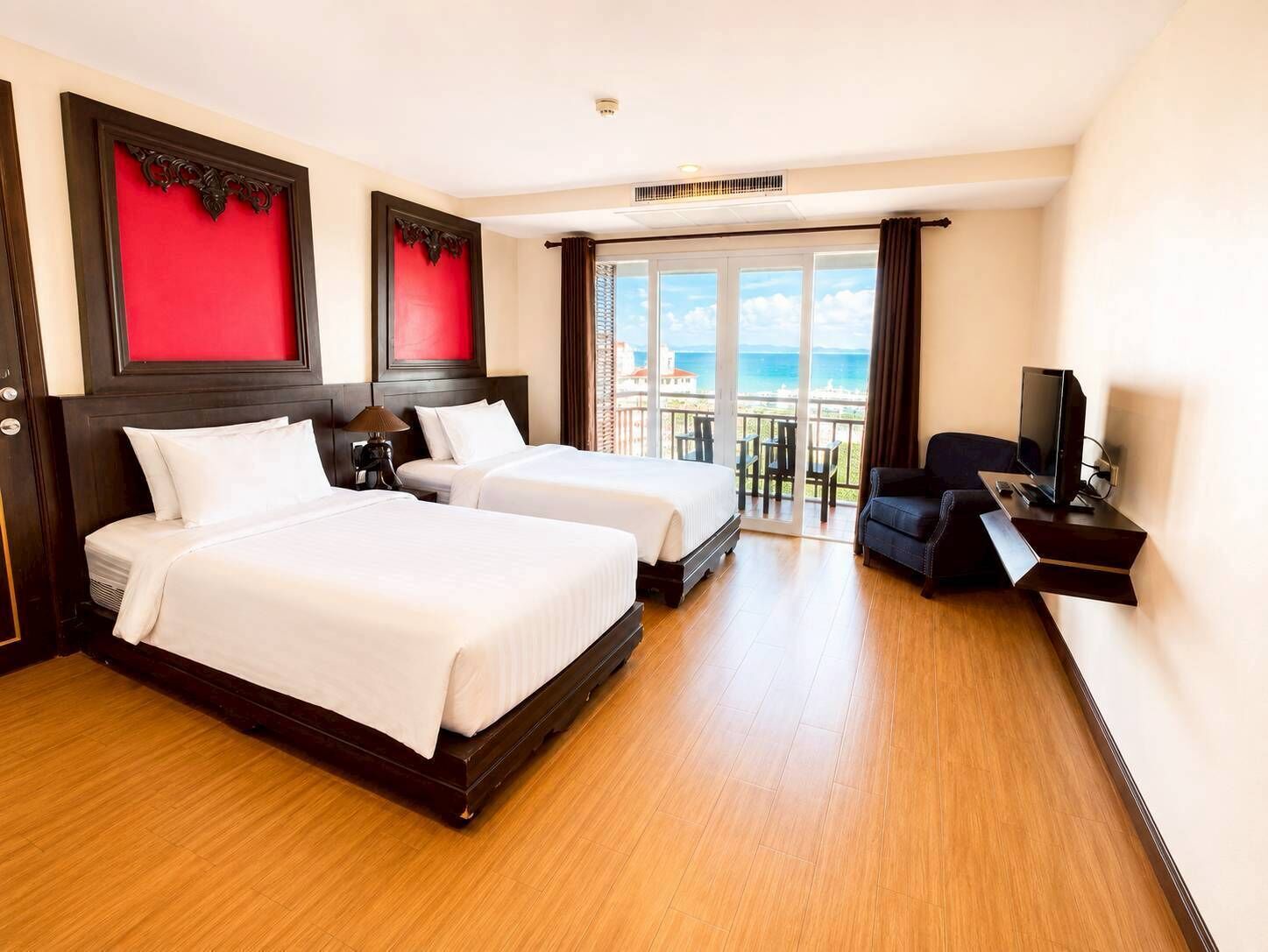 A hotel room with two beds, a TV, and a balcony with a view.