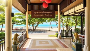 A covered outdoor area with a view of the beach, a sign with a message, and lion statues.
