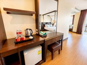 Hotelkamer met een houten bureau, een minibar, een bed met hemelbed en uitzicht op de stad door grote ramen.