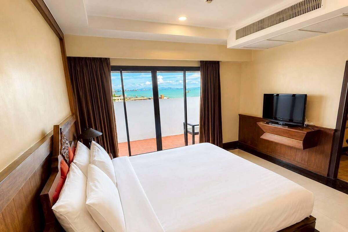 Een hotelkamer met een groot bed, een televisie en uitzicht op zee.