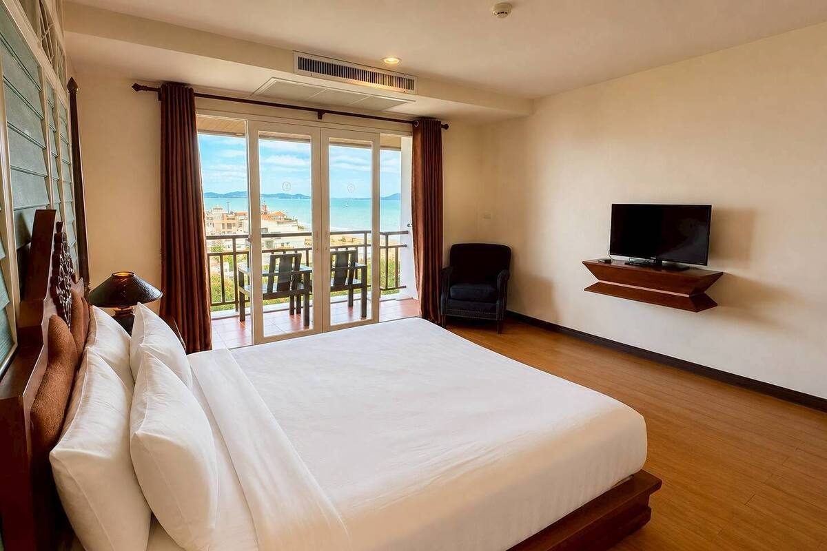 Een hotelkamer met een groot bed, een televisie, een stoel en een balkon met uitzicht.