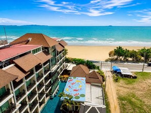 A hotel with multiple balconies, a swimming pool, and a beach view. - Royal Heritage Pavillion (Pattaya)