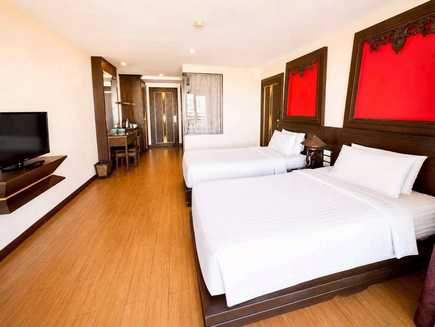 Ein Hotelzimmer mit zwei Betten, einem Fernseher, einem Schreibtisch und einem Stuhl.
