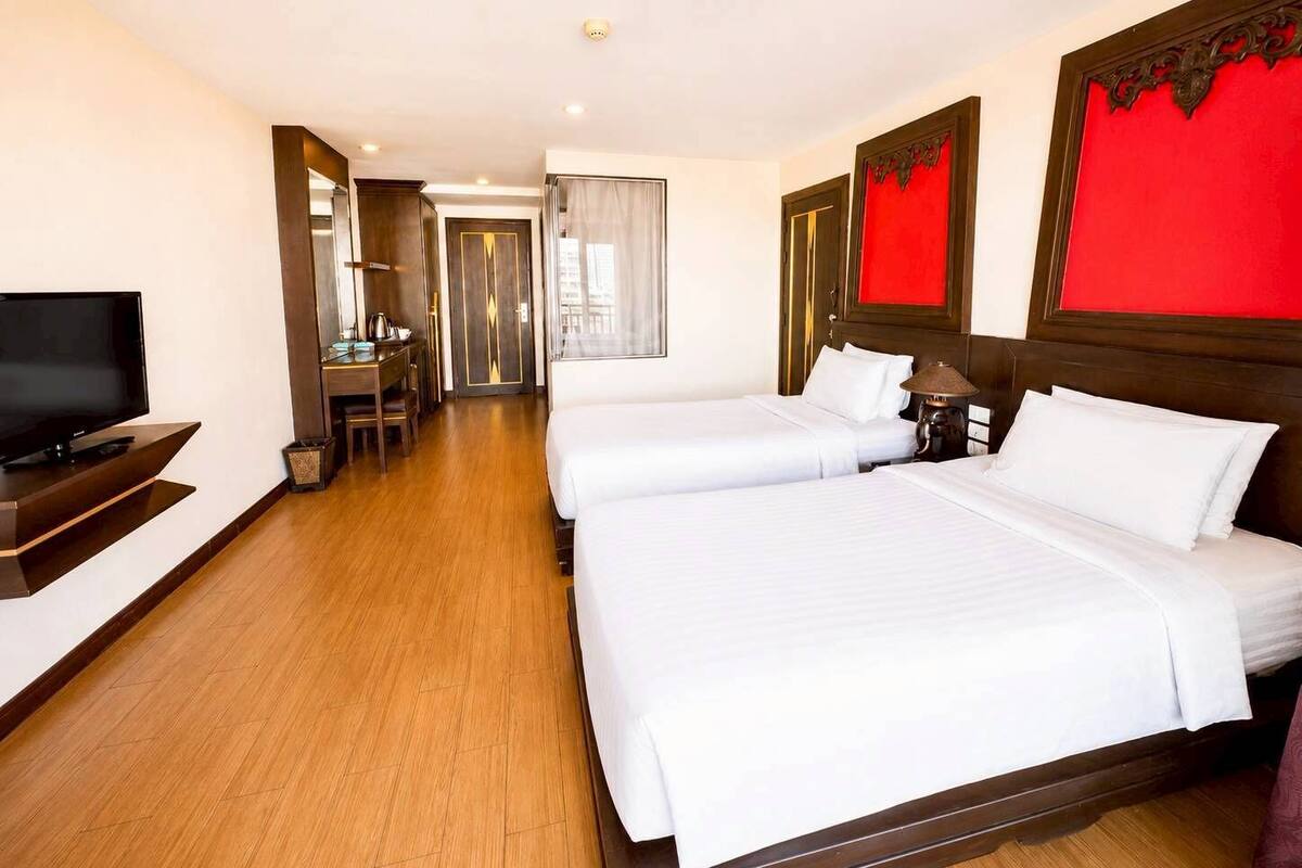 Een hotelkamer met twee bedden, een televisie, een bureau en een stoel.