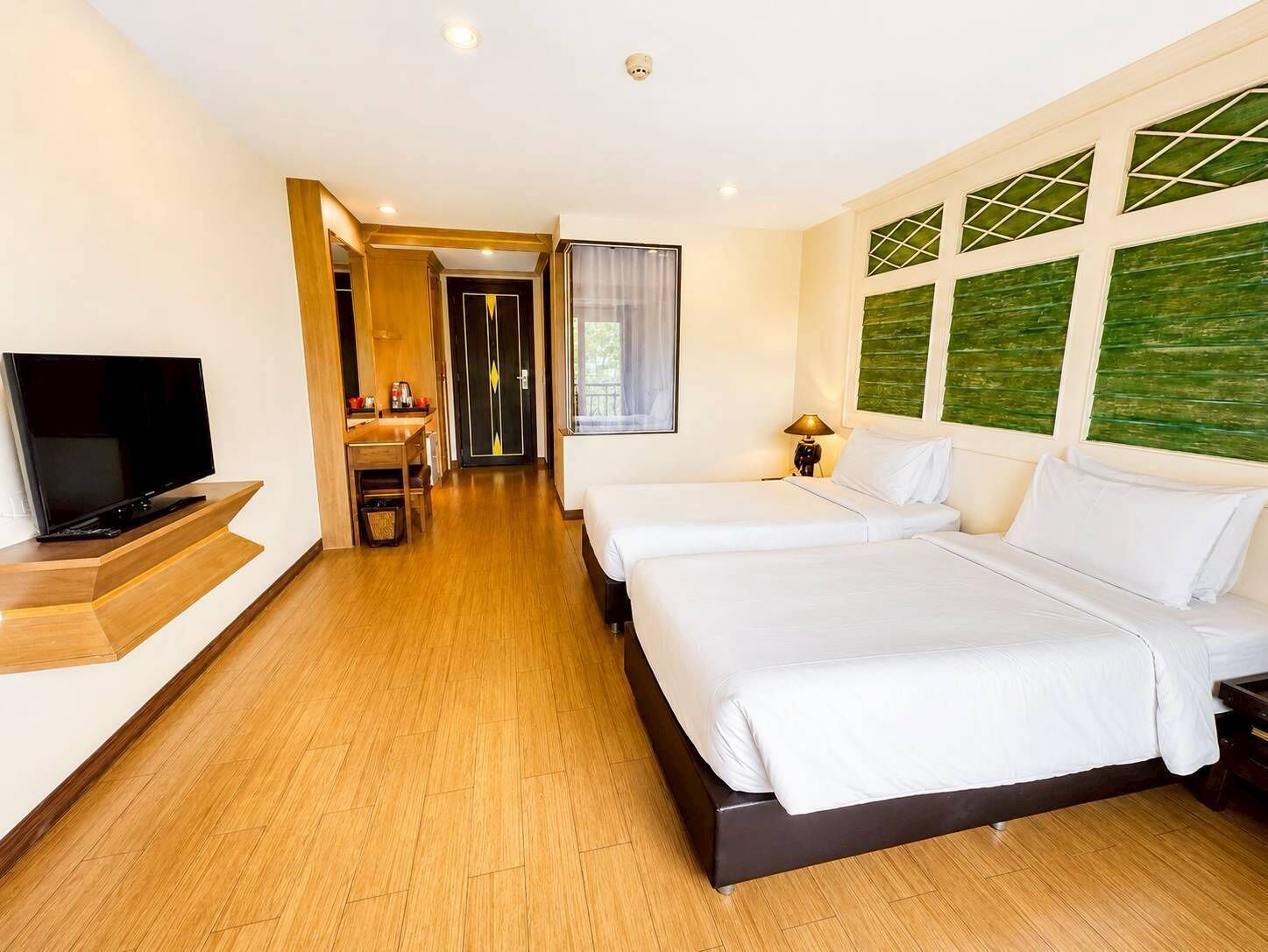 A hotel room with two beds, a TV, a desk, and a bathroom.