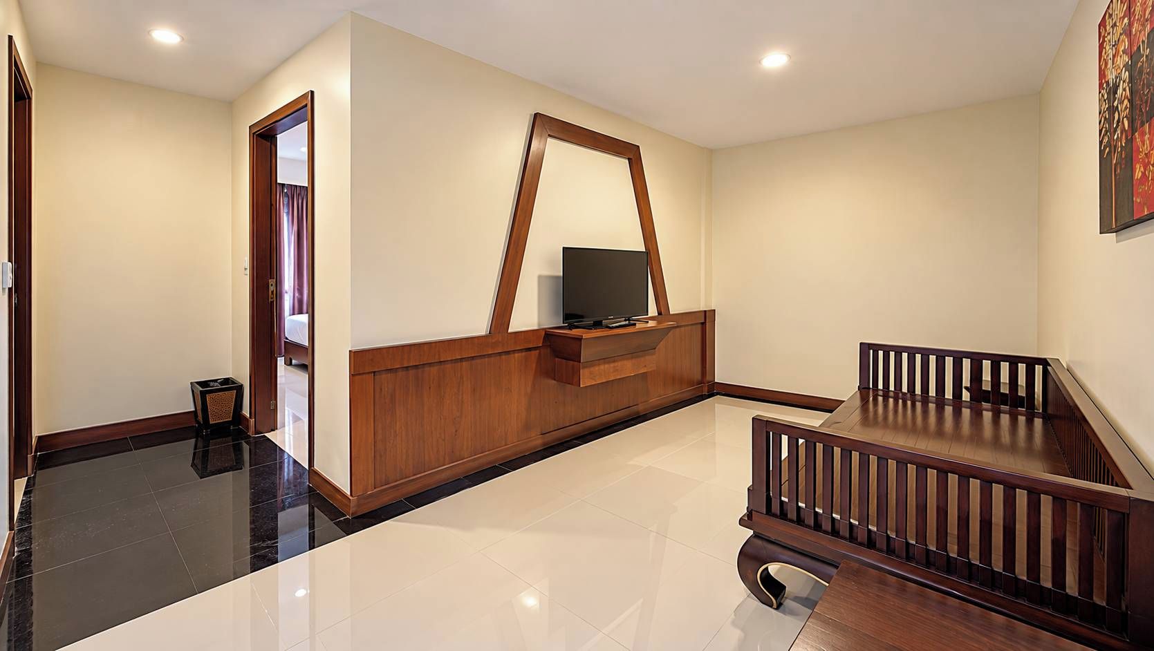 A hotel room with a wooden reception desk, a television, a small table, and a staircase.