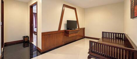 A hotel room with a wooden reception desk, a television, a small table, and a staircase.