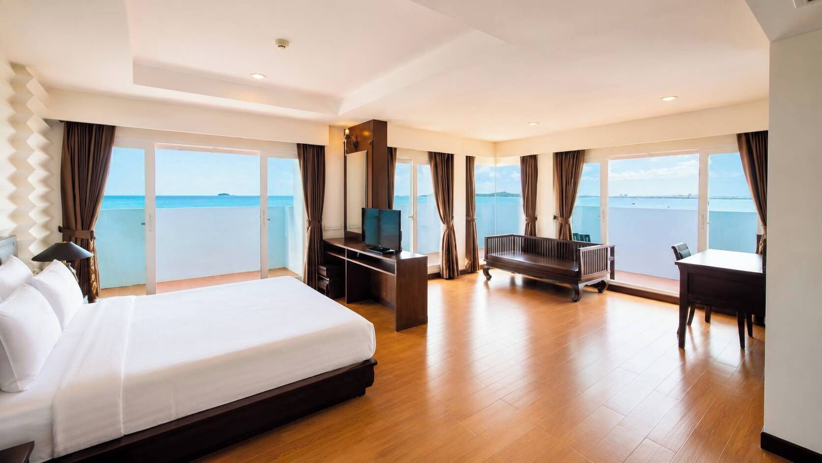 A spacious hotel room with a large bed, a desk, a TV, and a sofa.