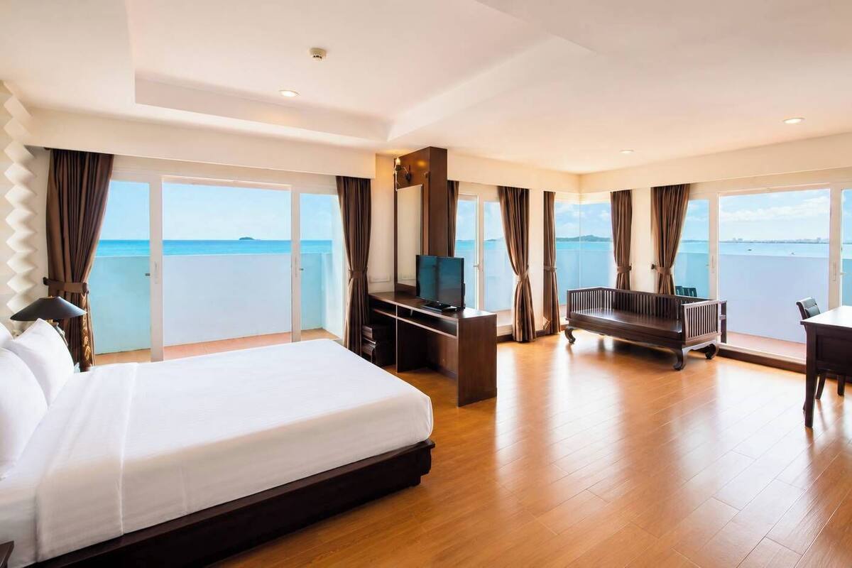 Ruime hotelkamer met een groot bed, een bureau, een televisie en een bank.