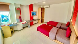 A modern hotel room with a large bed, a TV, a desk, and a wardrobe. - Tickle Hotel (Yogyakarta)