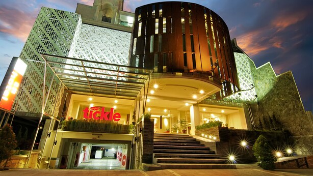 A modern hotel with a distinctive facade, a prominent entrance, and a staircase leading to the lobby. - Tickle Hotel (Yogyakarta)