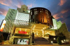 A modern hotel with a distinctive facade, a prominent entrance, and a staircase leading to the lobby. - Tickle Hotel (Yogyakarta)