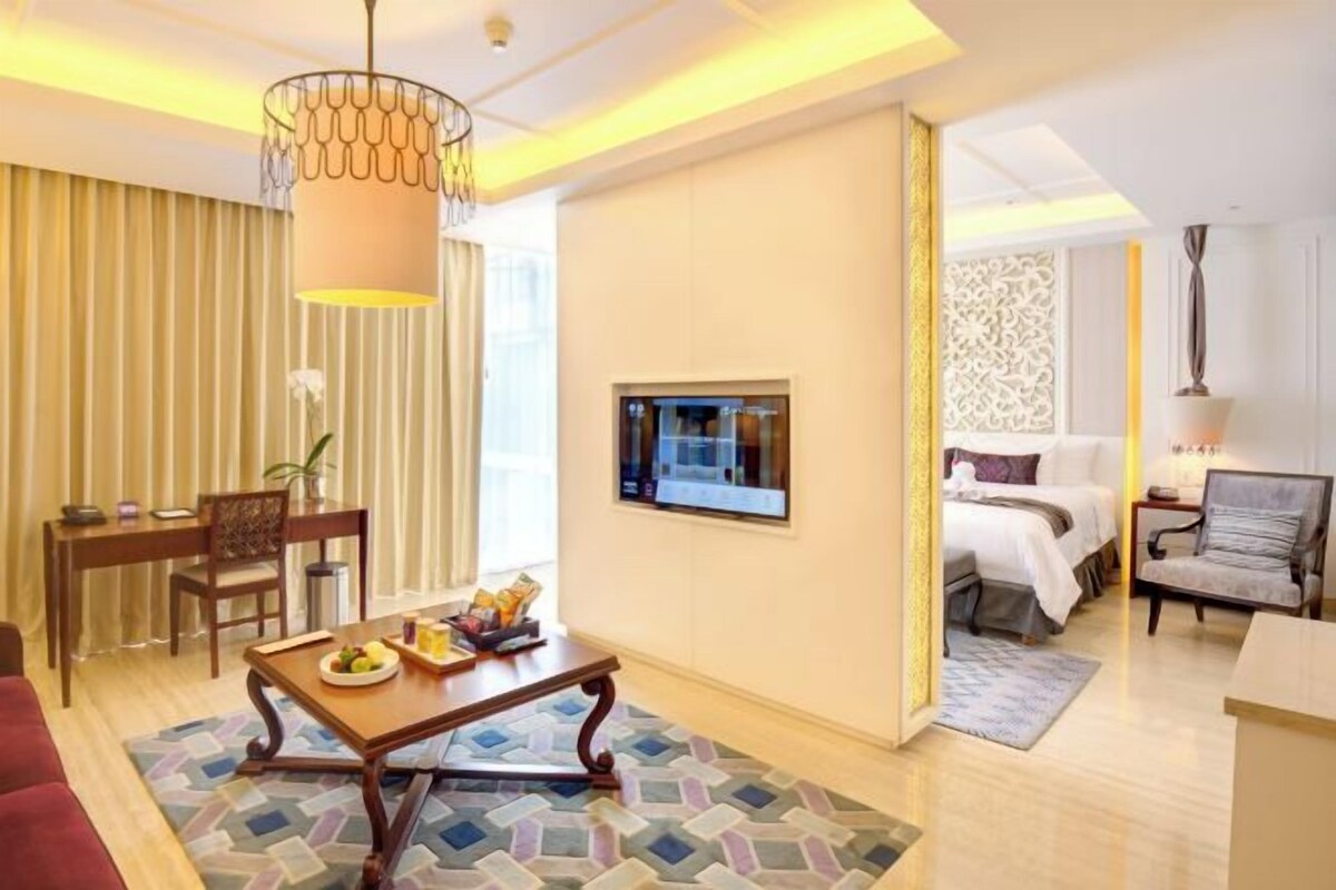A hotel room with a dining area, a bed, a TV, and a decorative wall panel.