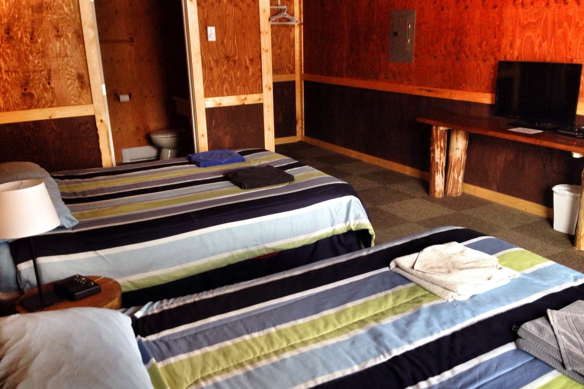 A hotel room with two beds, a desk, and a television.
