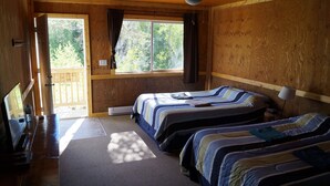 A room with two beds, a desk with a computer, and a window with curtains. - Mountain View Cabins (Golden)