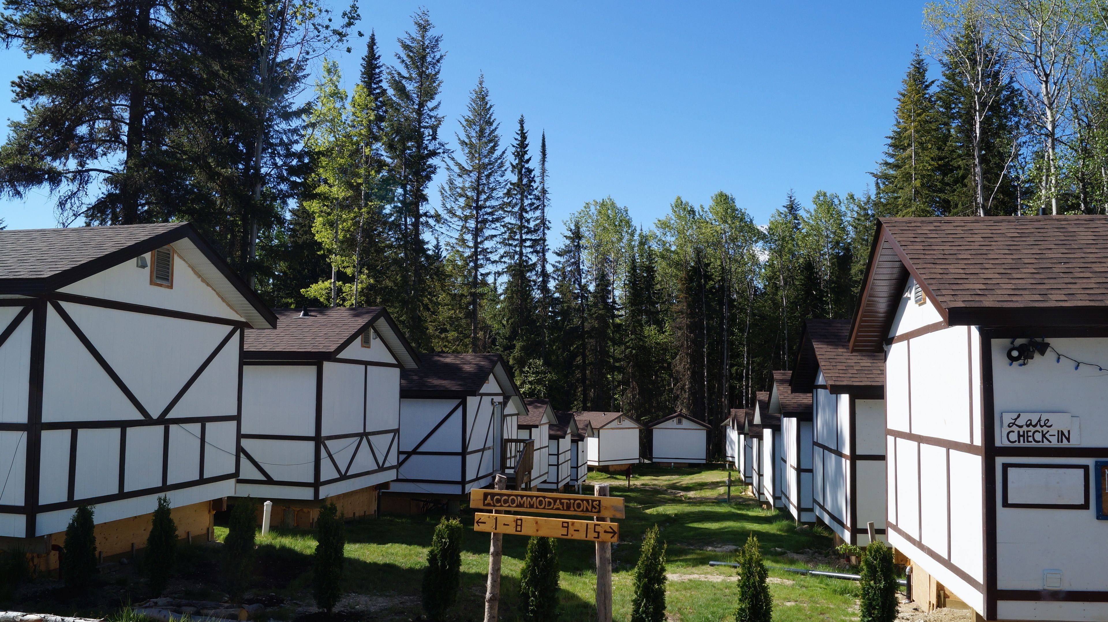 A row of traditional timber-framed cottages with a sign indicating accommodations available from 1-8 and 9-15.
