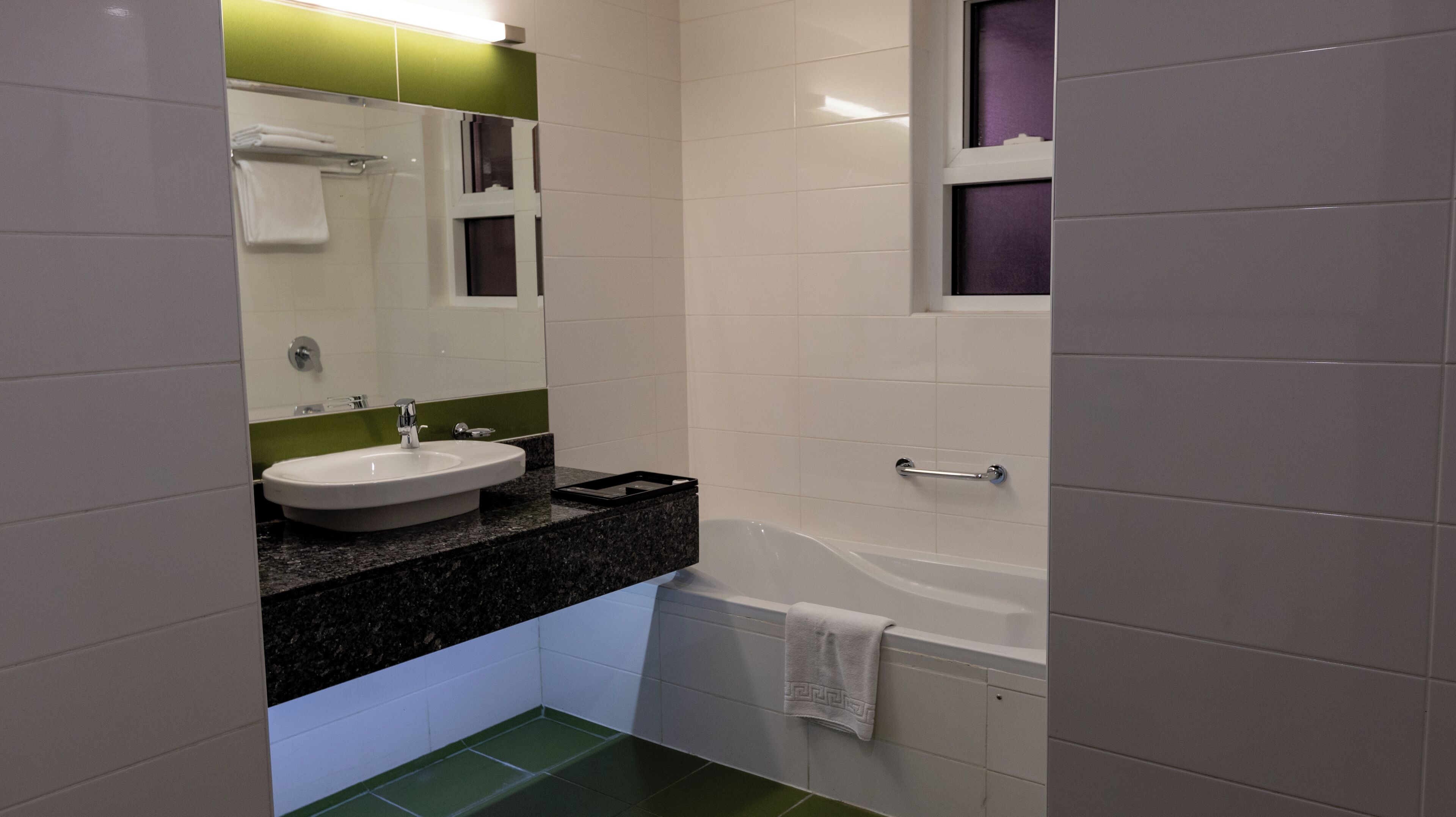 Un baño moderno con lavamanos blanco, un espejo y una bañera.