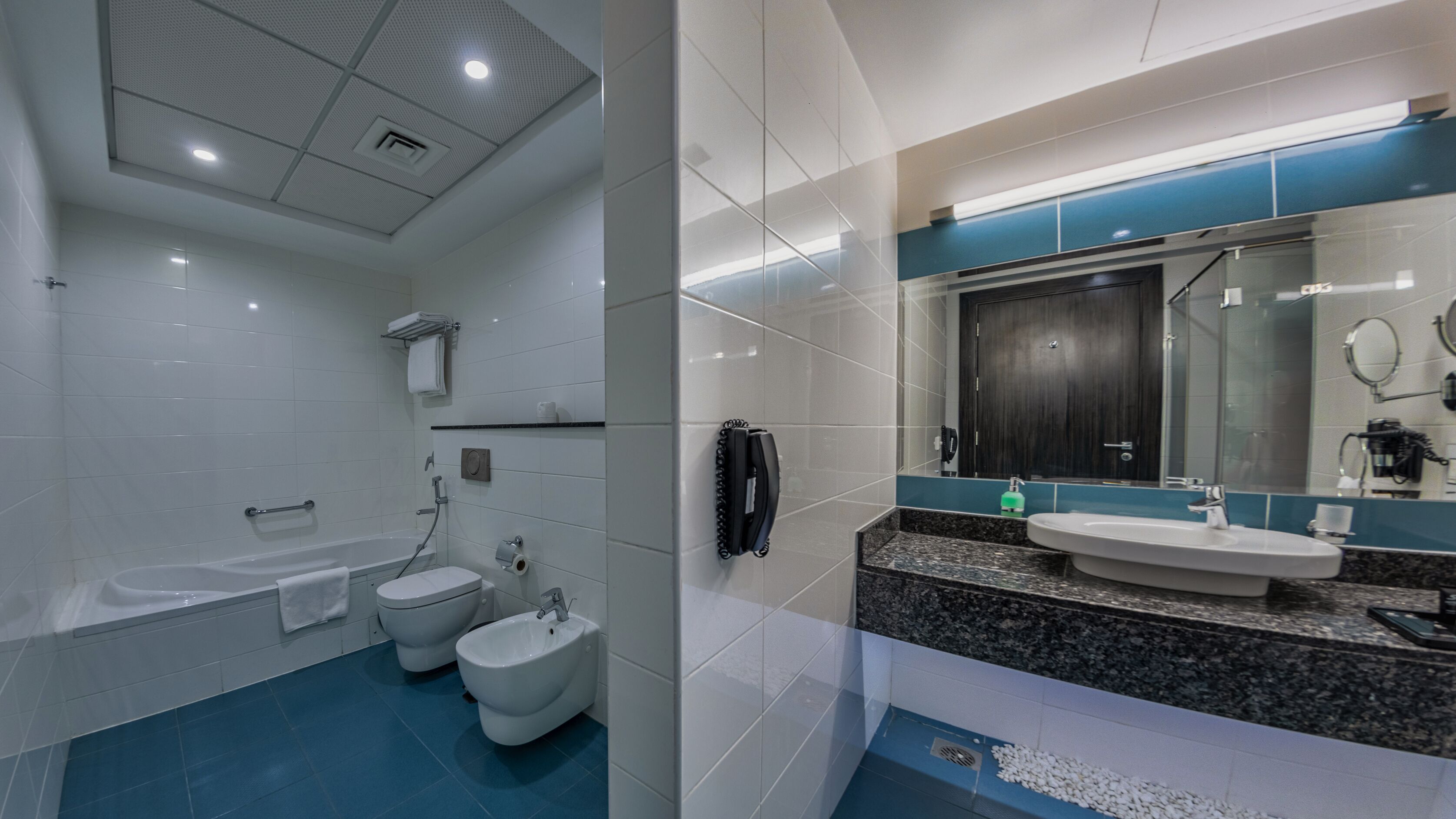 Un baño moderno con bañera, dos inodoros, un bidé, un lavabo y un espejo.