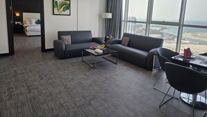 Et moderne hotelværelse med et stort vindue, der giver udsigt over by og strand.