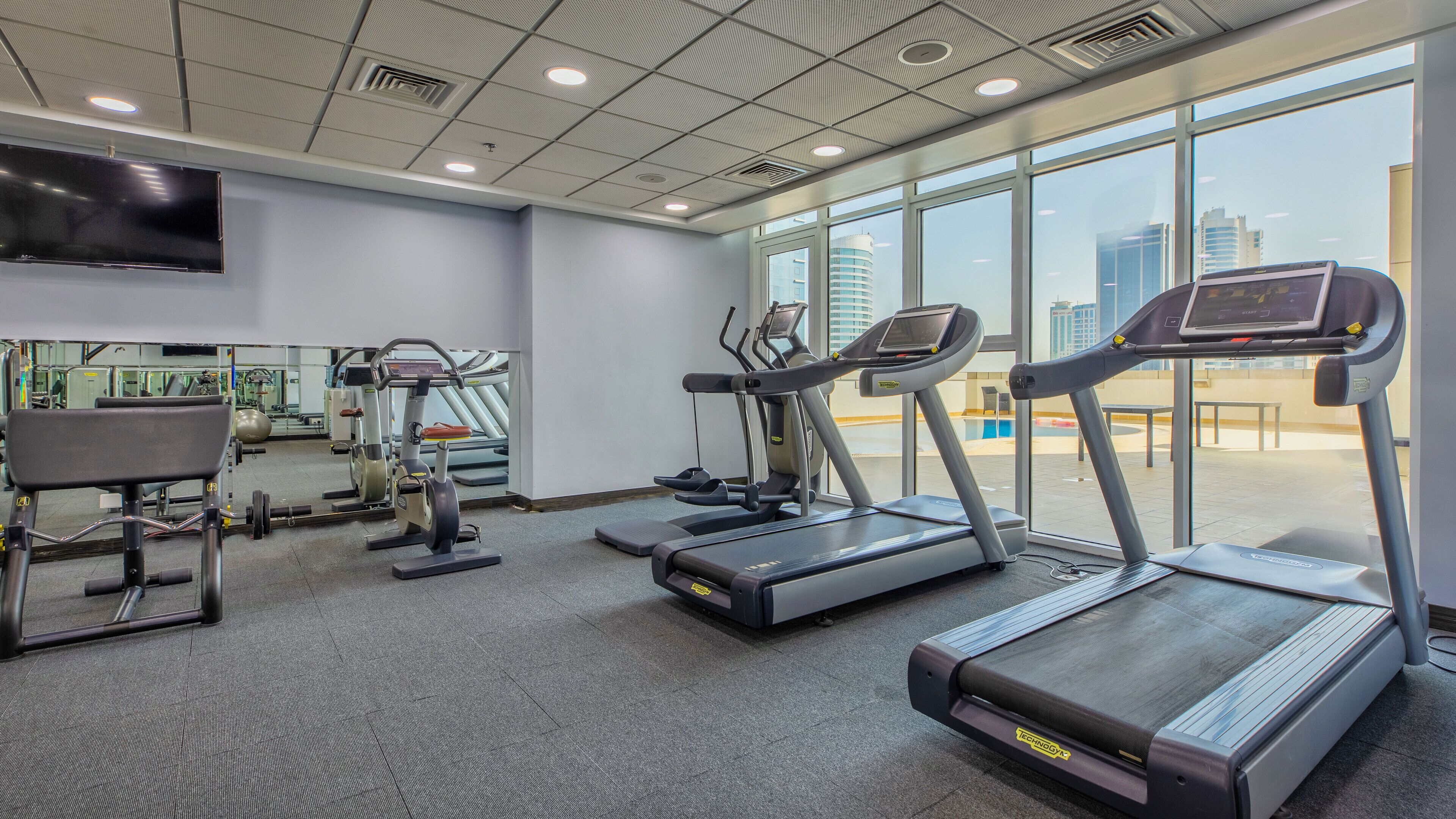 A gym with treadmills, elliptical machines, and a weight bench.