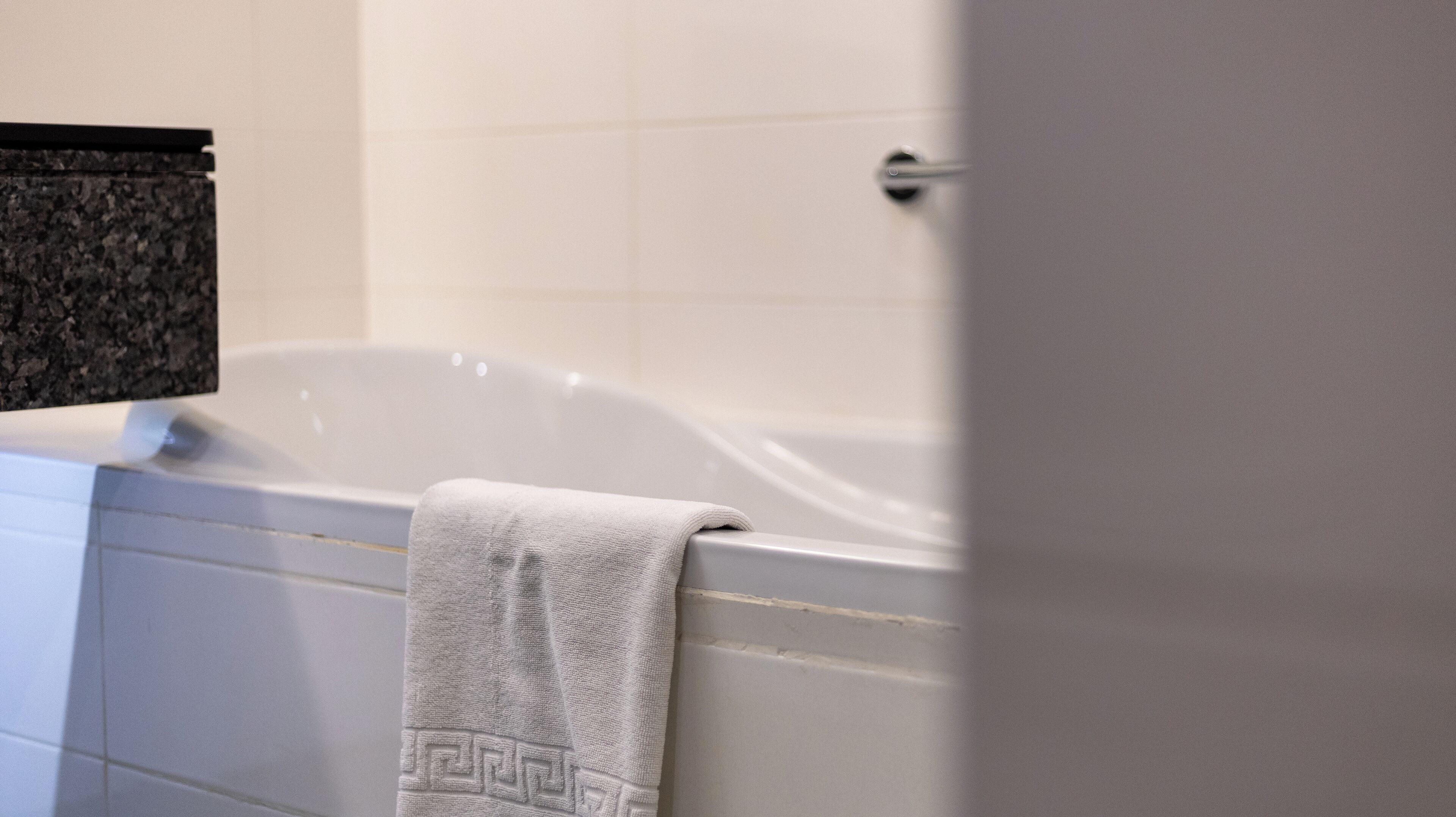 Ein Badezimmer mit einer Badewanne, einem Handtuch und einem Waschbecken mit einer Granittafel.