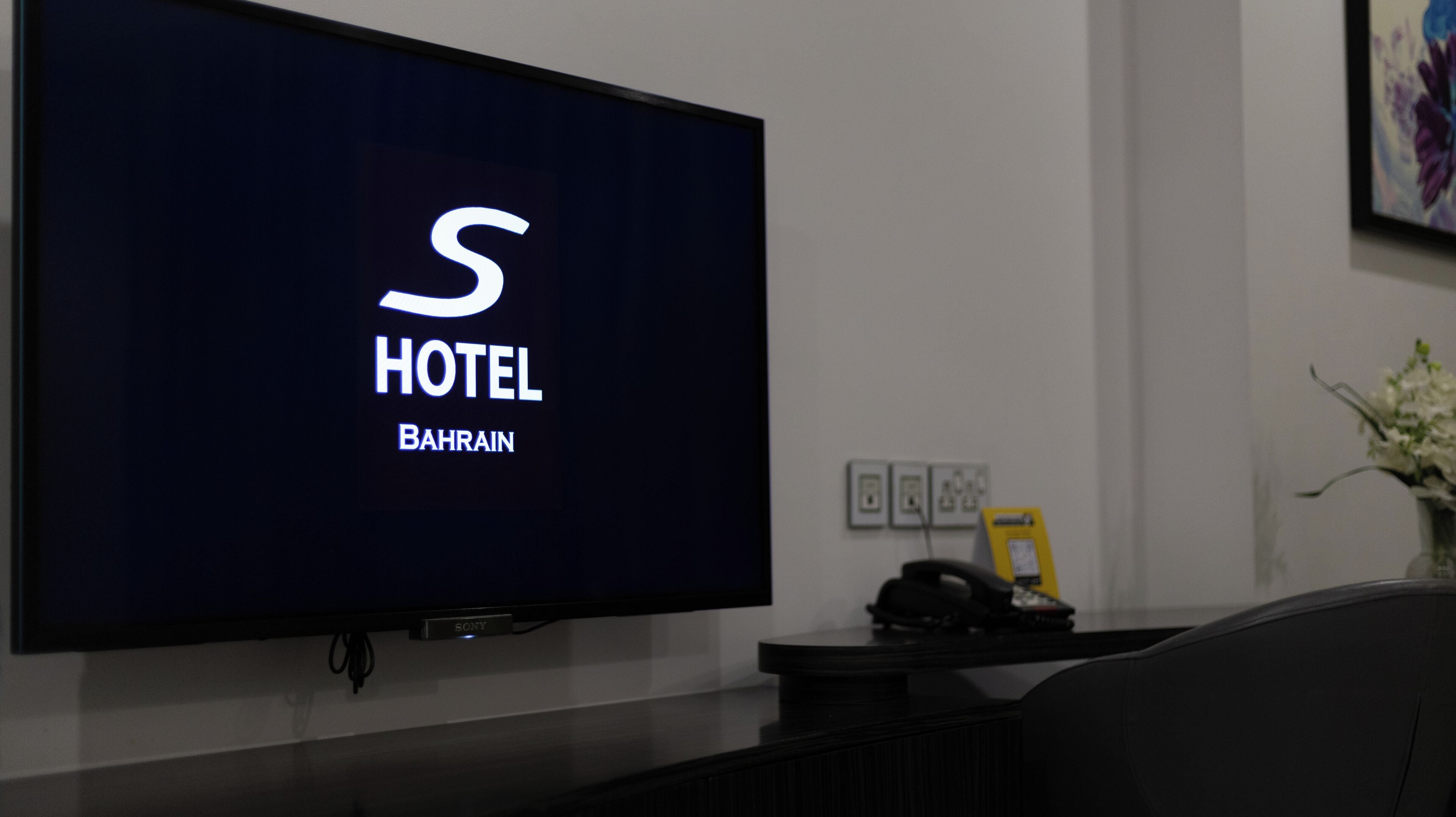 A flat-screen TV displaying a hotel sign with the letter 'S' and the words 'HOTEL BAHRAIN'.