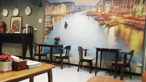 A room with a mural of a river scene, a wooden table, several chairs, and a sofa. - Naturbliss Boutique Residence (Bangkok)