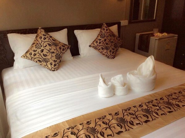 Una cama bien hecha con almohadas estampadas y un corredor decorativo.