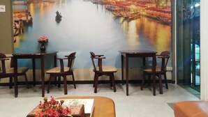 A restaurant with a mural of a river scene, wooden chairs, and a small table with a vase of flowers. - Naturbliss Boutique Residence (Bangkok)