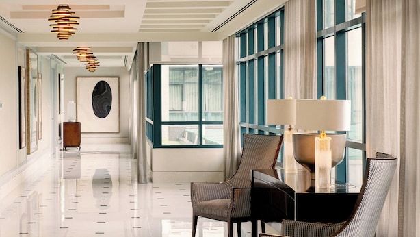 Un hall d’hôtel moderne, doté d’un sol ciré, de grandes fenêtres et de mobilier contemporain.