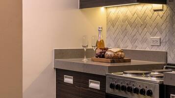 A modern kitchen with a built-in oven, a wine glass, a bottle of wine, and a loaf of bread on the counter.