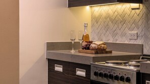 A modern kitchen with a built-in oven, a wine glass, a bottle of wine, and a loaf of bread on the counter.