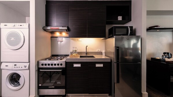 A compact kitchen with a built-in washer, stove, microwave, and refrigerator.