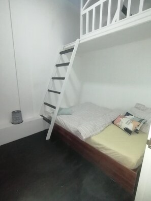 A room with a bunk bed, a ladder, a small trash bin, and a single bed with pillows. - X-Plorer Backpackers - Hostel (Kota Kinabalu)