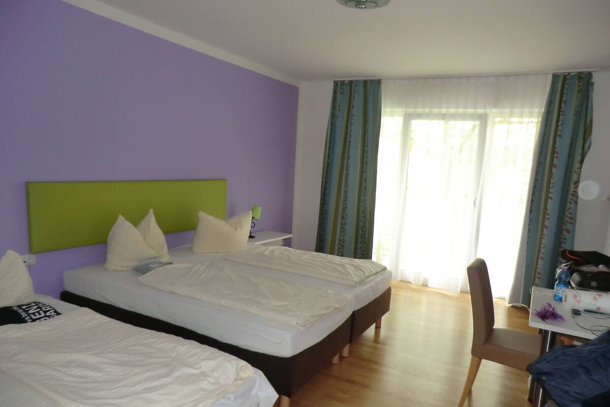 A hotel room with two beds, a desk, and a chair.