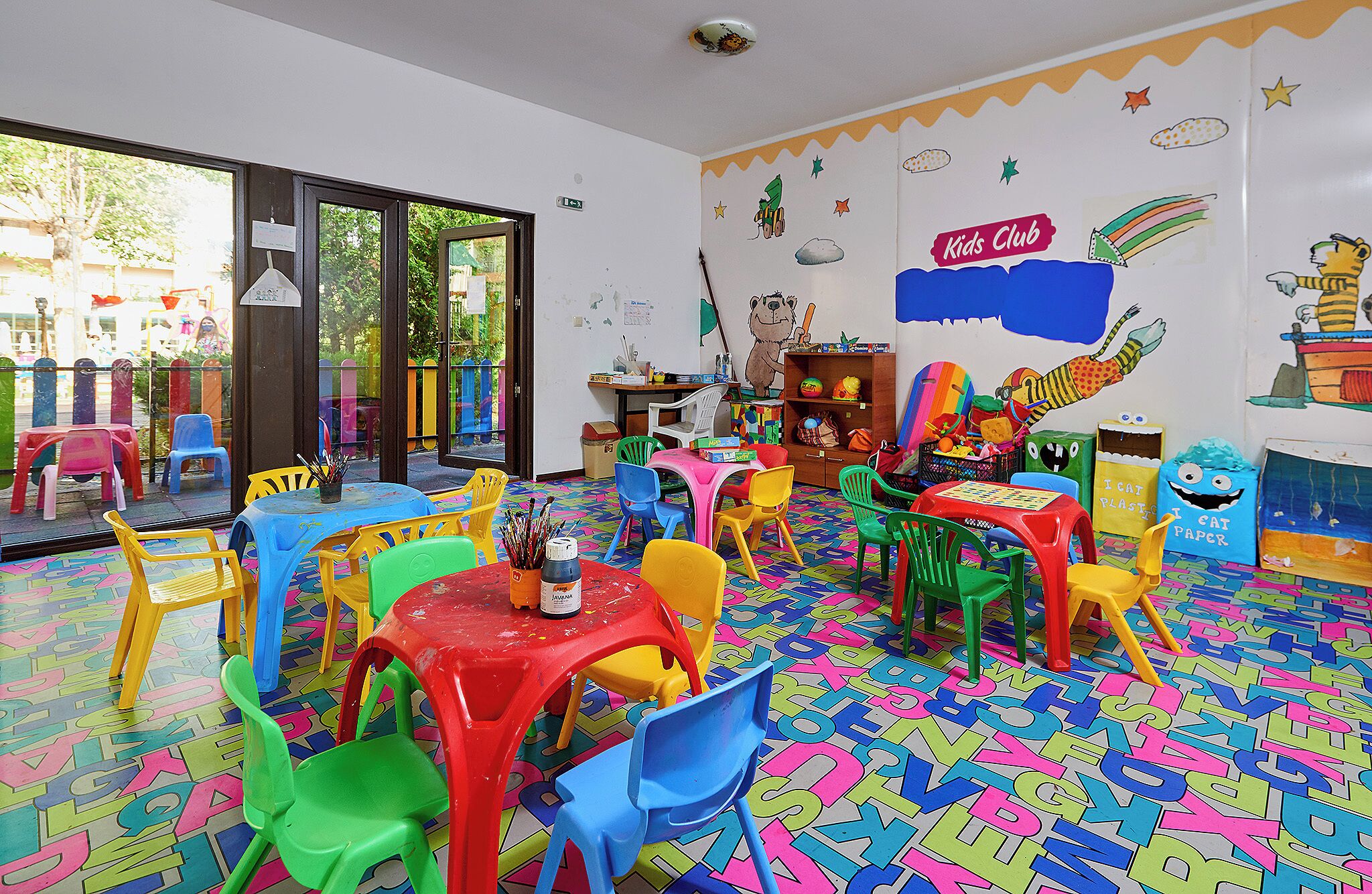A children's playroom with colorful furniture and a playful wall design.