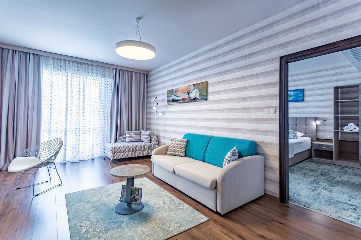 A modern living room with a sofa, a chair, a coffee table, and a painting on the wall.