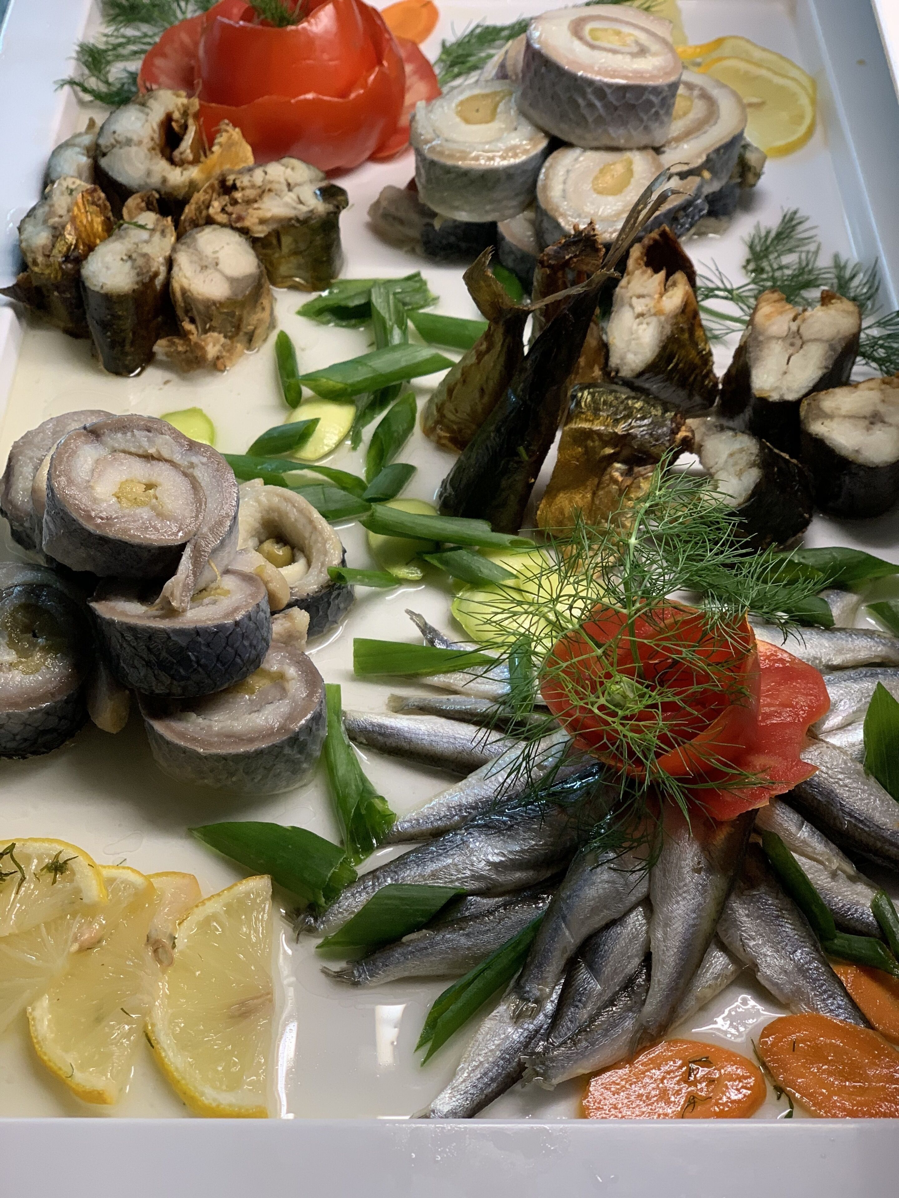 Un grand plat de fruits de mer variés, comprenant du poisson, des crevettes et des œufs de poisson, agrémenté d’herbes et de tranches de citron.