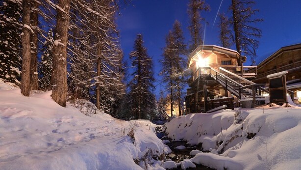 A snow-covered landscape with a wooden cabin and a stream. - Hôtel Les Escondus (Vars)