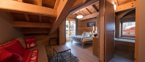 Ein gemütliches Blockhaus mit Schlafzimmer im oberen Bereich, einem Wohnbereich mit einem roten Sofa und einem Essbereich.
